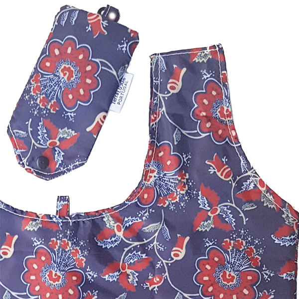 The “Chita” From Alcobaça Eco Shopper by Terra Lusa features a reusable bag and matching pouch, both adorned with a purple, red, and light blue floral pattern. The bag folds into the snap-closure pouch with tag for easy storage.