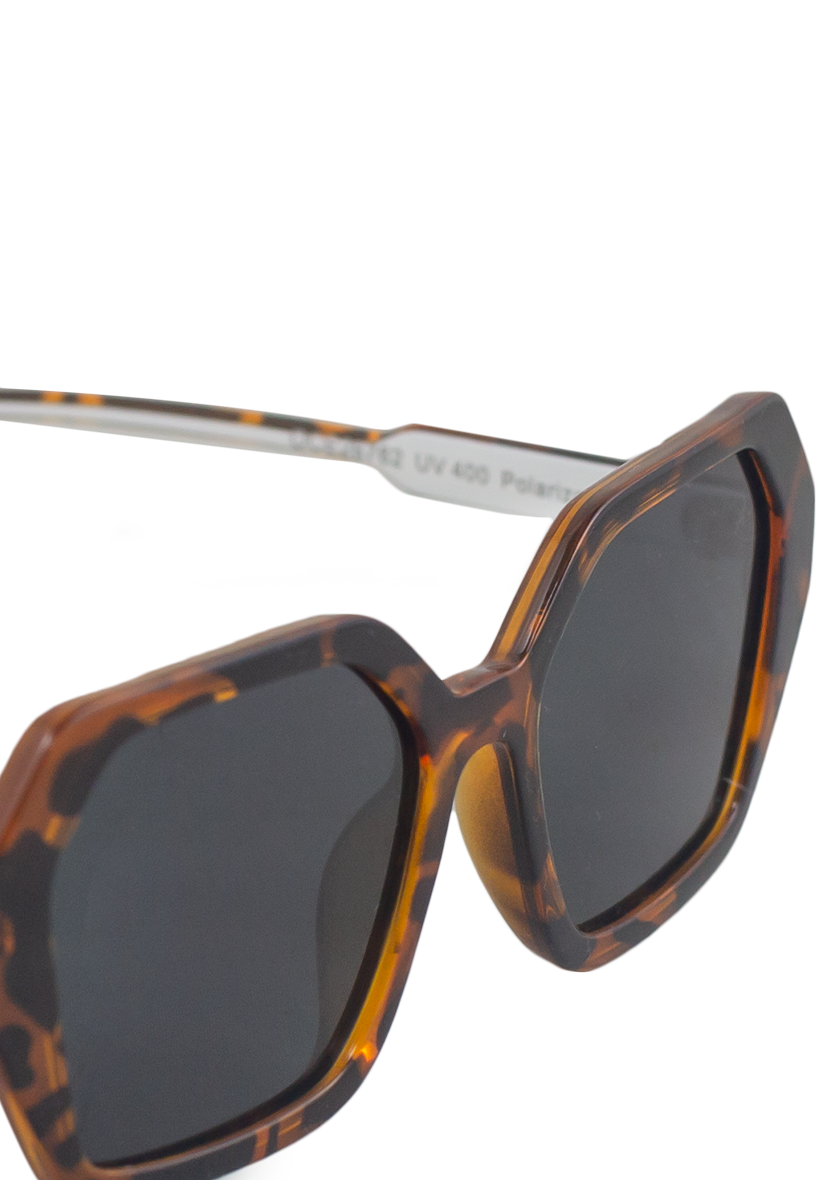 Close-up of Oceanides Coral Dark Havana Sunglasses featuring oversized geometric frames in a tortoiseshell pattern and dark polarized lenses, displayed against a plain white background.