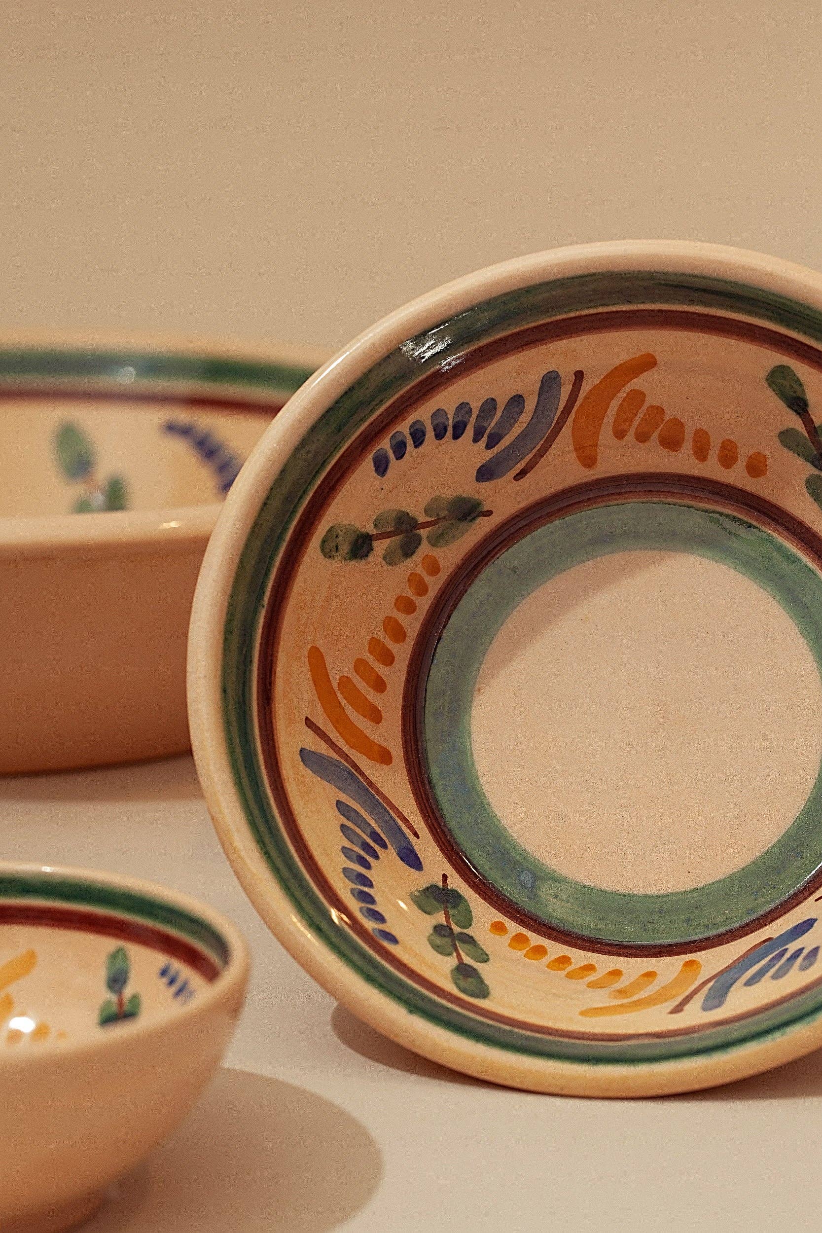 The Medina Printed Ceramic Bowl by Eturel Madrid is showcased upright against a beige background, highlighting its hand-painted green, blue, orange, and yellow Andalusian-inspired patterns.