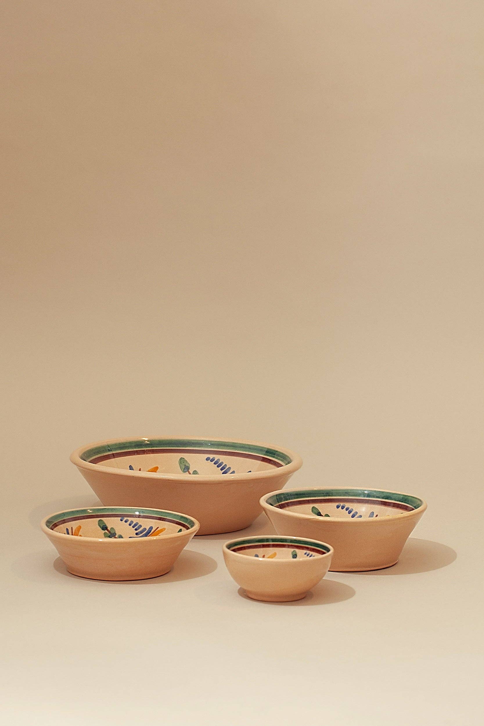Four Eturel Madrid Medina Printed Ceramic Bowls in varying sizes, featuring painted floral designs and green rims, are arranged on a neutral beige background.
