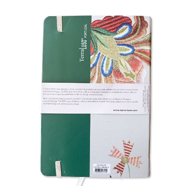 The Castelo Branco Quilt Notebook by Terra Lusa features a green and white cover with colorful embroidered floral designs inspired by Portuguese heritage, an elastic band, and a center label describing the product and brand.