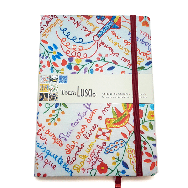 The Lovers’ Handkerchiefs Notebook by Terra Lusa features a colorful Portuguese floral and bird embroidery design, secured with a red elastic band. Inspired by Minho handkerchief notebooks, it’s part of Terra Lusa’s themed collection.
