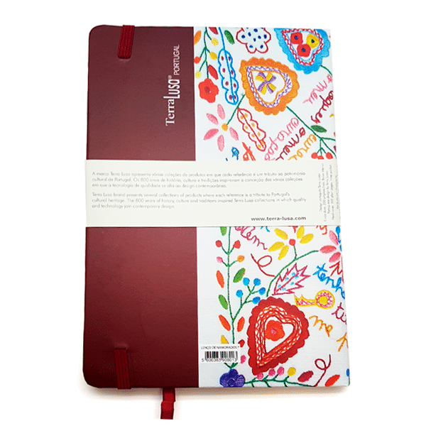 The red Lovers’ Handkerchiefs Notebook by Terra Lusa features a colorful, hand-drawn floral and heart design with a white paper band showing the brand name and text, celebrating Portuguese handicraft tradition.