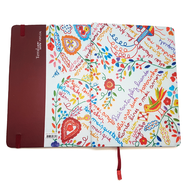 The Lovers’ Handkerchiefs Notebook by Terra Lusa features a maroon spine and cover with vibrant, embroidered-style flowers, hearts, a bird, and colorful handwritten words on the front.