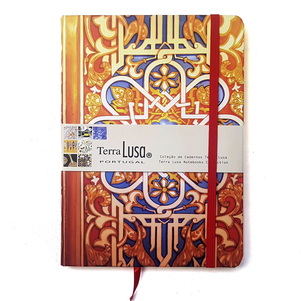 The Terra Lusa Stained Glass Notebook features a vibrant, tile-inspired cover with a red elastic band and ribbon, celebrating Portuguese Cultural Heritage. A branded label wraps the front, showcasing the product and design details.