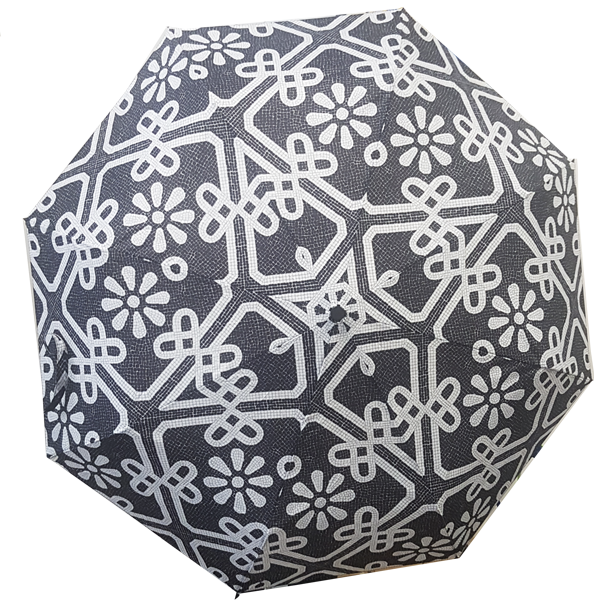 The Terra Lusa Sidewalk Umbrella features a black calçada pattern with white geometric lines and stylized flowers, inspired by traditional Portuguese sidewalks, covering its entire surface.