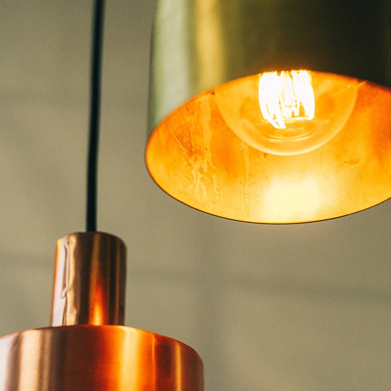 Close-up of two Seber Lamps by Hannun in metallic finishes—brass and copper—both glowing warmly, ideal for industrial-inspired interiors. Available in 3 colours.