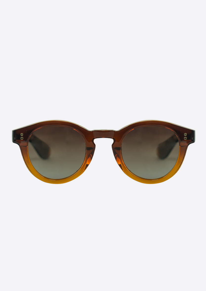 Oceanides Sunglasses (Polarized) – Rodea Crystal Gradient Brown feature a transparent amber recycled plastic frame, dark gradient lenses, and subtle metallic corner accents, shown on a plain white background.