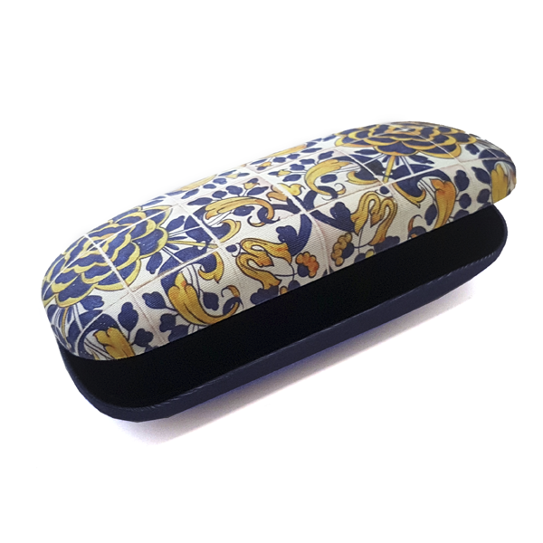 The Terra Lusa Box For Glasses "Tile" Camellia is a hard case with a vibrant Portuguese-inspired floral and geometric pattern in yellow, blue, and white; it is partially open to show its dark interior.