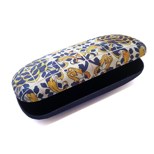 The Terra Lusa Box For Glasses "Tile" Camellia is a hard case with a vibrant Portuguese-inspired floral and geometric pattern in yellow, blue, and white; it is partially open to show its dark interior.