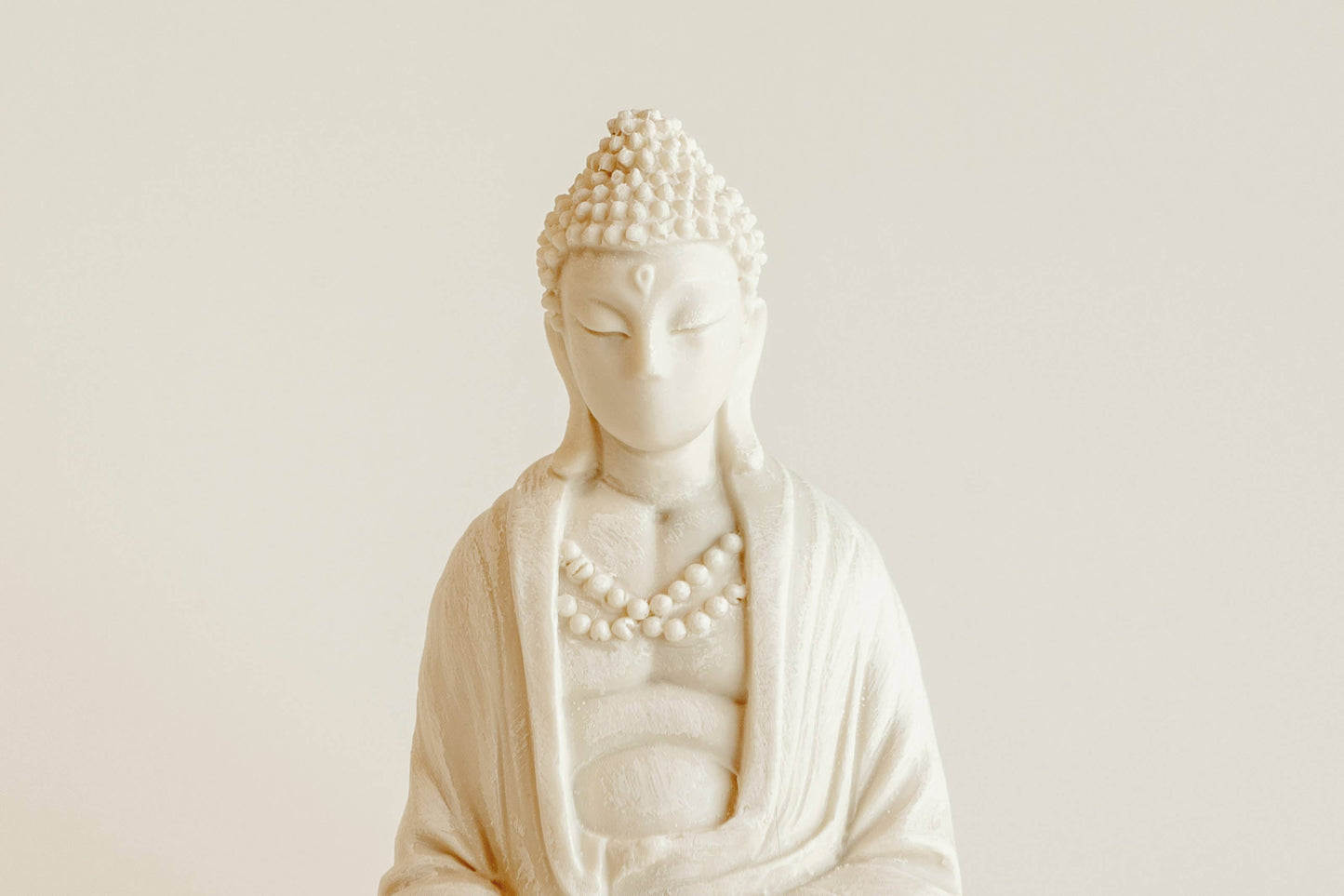 The Manulena Decorative & Aromatic Buddha Piece (White) features closed eyes, curly hair, and a beaded necklace—offering serene decor that doubles as a scented Buddha with Exotic Orchid Fragrance.