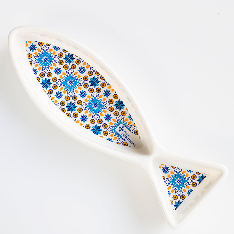 The Olives serve 'Sardine 16' Dish by ObjectoAnonimo is a white ceramic fish-shaped plate with blue, yellow, and orange geometric and floral patterns inside—perfect for serving olives in Portuguese style.