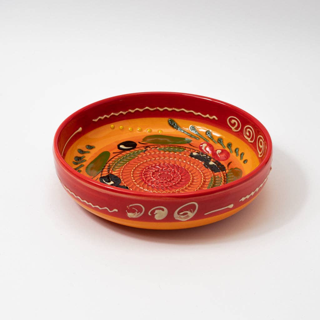 The Alfar Tierra Cocida Ceramic Grater Plate/Vintage Andalusian Provenzal is a round, shallow plate handmade in Spain with a bright orange interior, red rim, colorful hand-painted patterns, and white swirl designs on the edge.