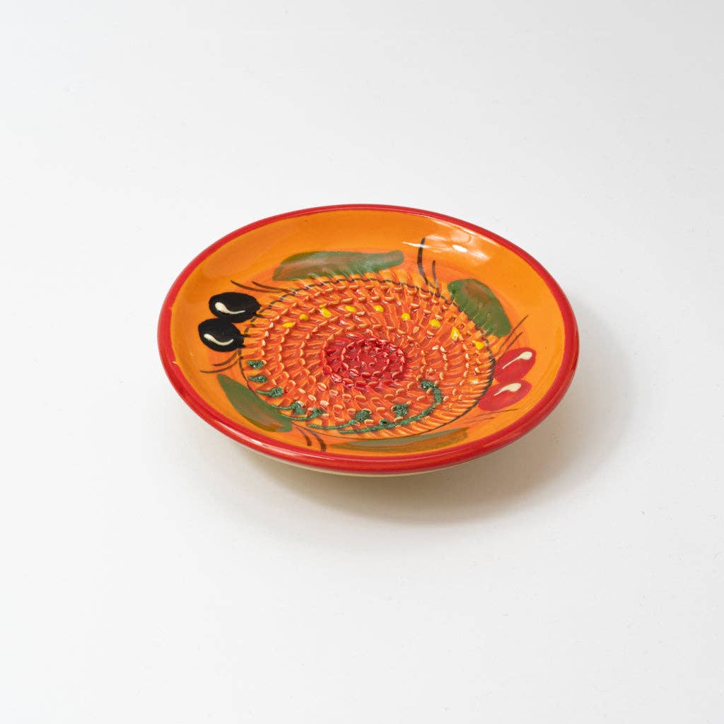The Alfar Tierra Cocida Ceramic Grater Plate/Vintage Andalusian Provenzal is a small, handmade Spanish plate with an orange spiral-textured center for grating and hand-painted fruit and leaf motifs around the rim, shown on a white surface.
