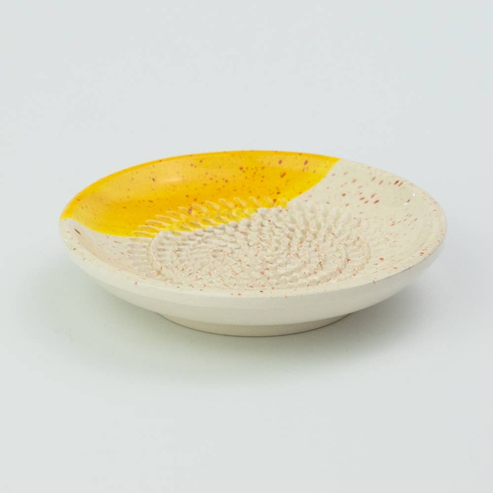 The Alfar Tierra Cocida Ceramic Cheese and Vegetable Grater Plate/Nuevo Canela is a handmade Spanish dish with a textured center for grating, a speckled cream base, vibrant yellow accent, and raised rim—ideal as a decorative vegetable grater.