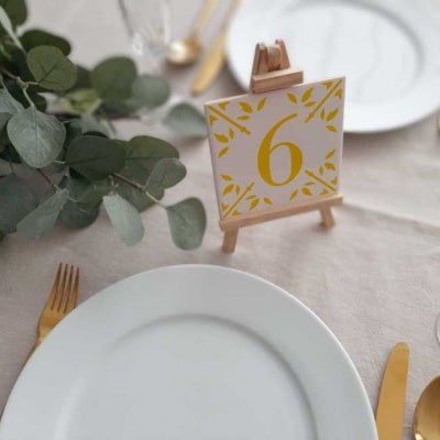 hand painted ceramic tile with a yellow number 6 on a miniature display easel