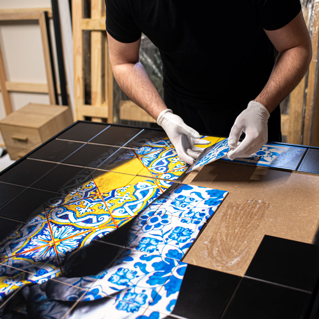 Person working with tiles and a patterned fabric on a table.