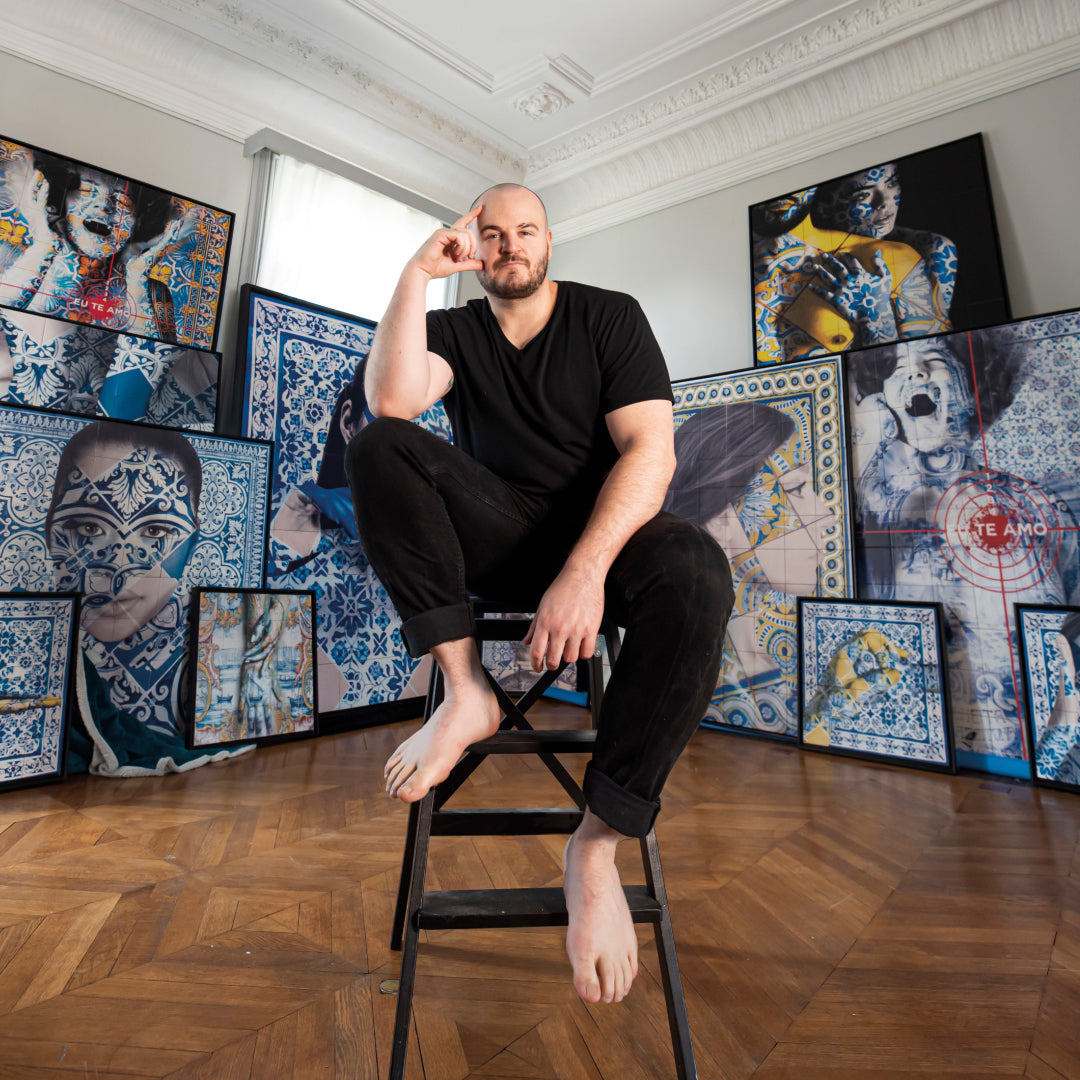 Man sitting on a stool in a room with artistic wall decorations