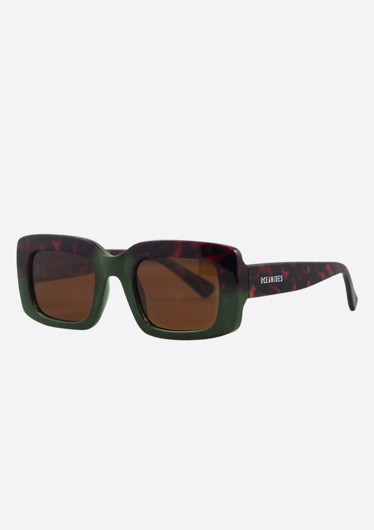 Oceanides Sunglasses (Polarized) - Ida Tortoise Green Brown feature a thick rectangular frame: green front, dark tortoiseshell sides, and "OCEANIDES" in white on the left arm. Sustainable eyewear for effortless style.