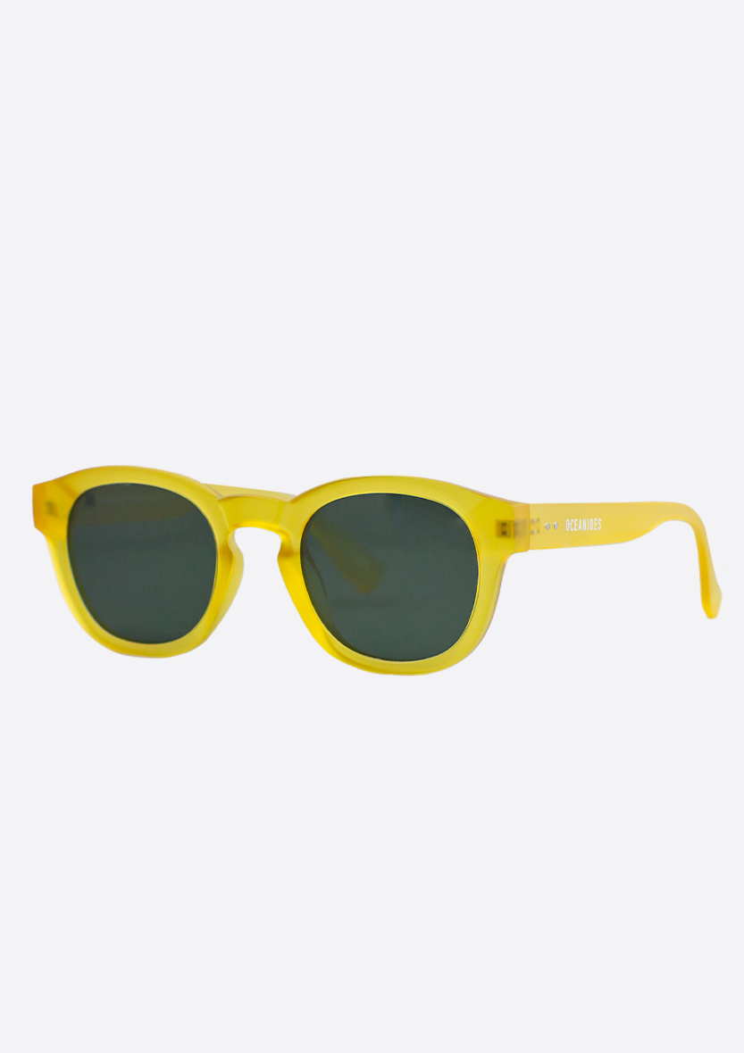 The Oceanides Atlas Yellow Frosted Sunglasses feature round dark lenses and a thick recycled plastic frame, shown at an angle against a plain white background.