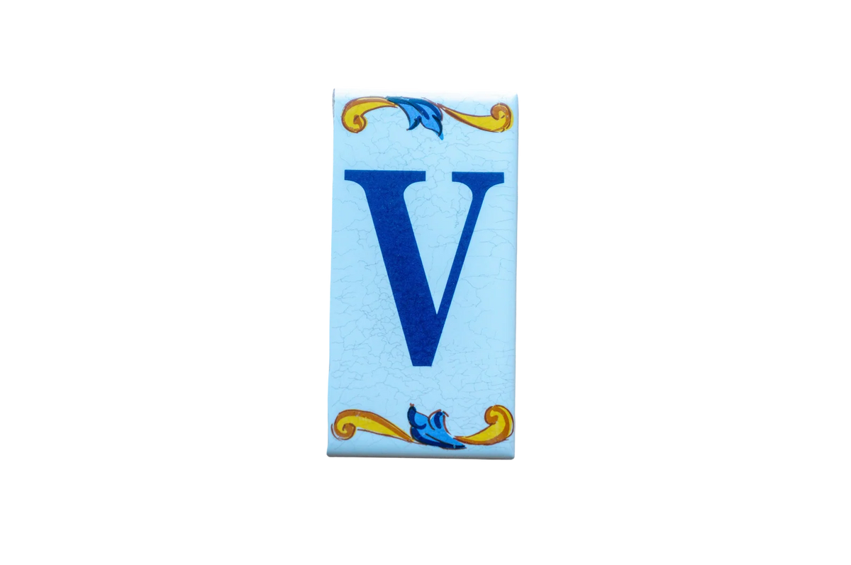 Lisa Croquets Letters – Ceramic House Letter Tiles rectangular ceramic tile featuring a blue letter V with handcrafted decorative yellow and blue scrolls at the top and bottom.
