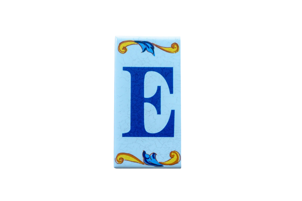 Lisa Croquets Letters – Ceramic House Letter Tiles rectangular tile featuring a large dark blue E centered between decorative blue and gold scrollwork accents on a light blue background.