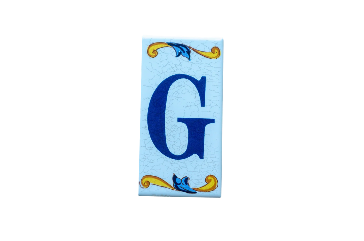 Lisa Croquets Letters – Ceramic House Letter Tile featuring a blue G, decorative blue and yellow scrollwork, and a light blue cracked background.