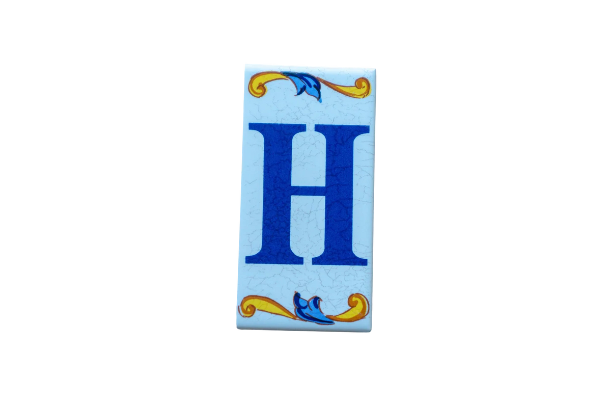 Lisa Croquets Letters – Ceramic House Letter Tile featuring a large blue H centered on a rectangular surface with decorative blue and yellow floral motifs at the top and bottom.