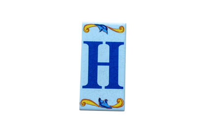 Lisa Croquets Letters – Ceramic House Letter Tile featuring a large blue H centered on a rectangular surface with decorative blue and yellow floral motifs at the top and bottom.