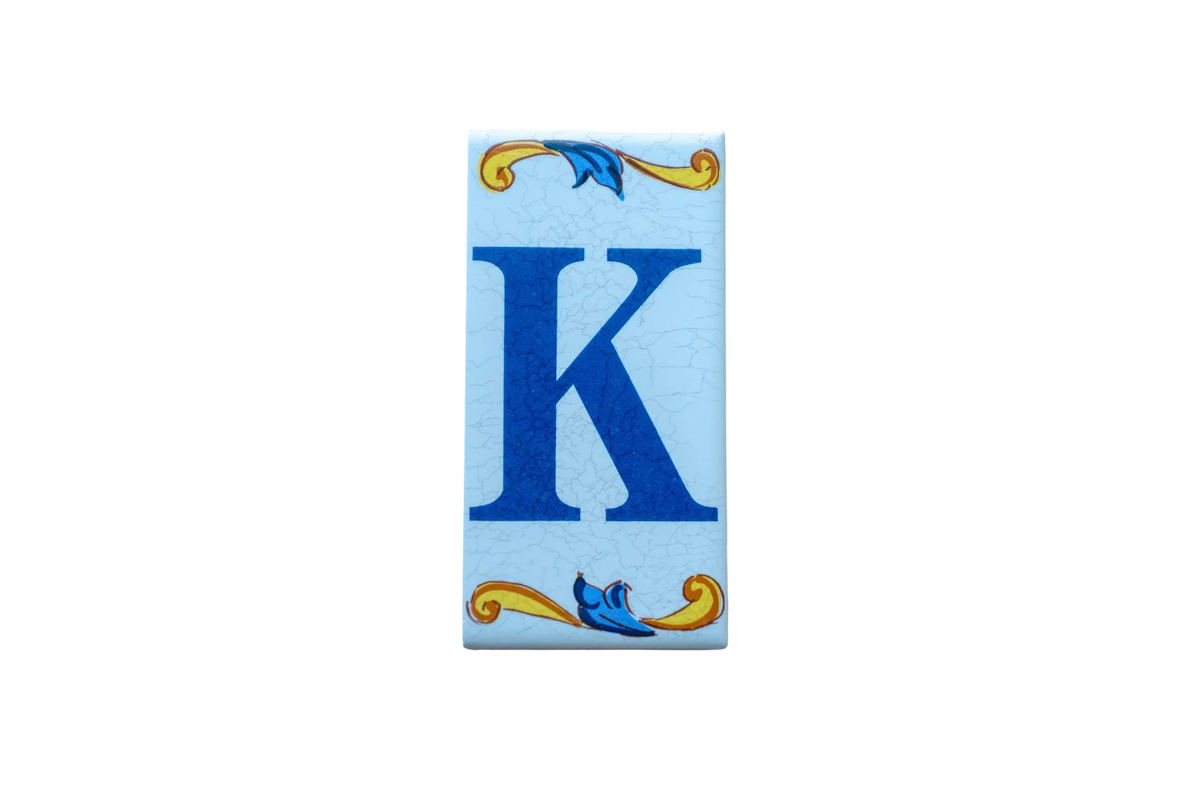 Lisa Croquets Letters – Ceramic House Letter Tile featuring a rectangular blue letter K decorated with blue and yellow scrollwork at the top and bottom.