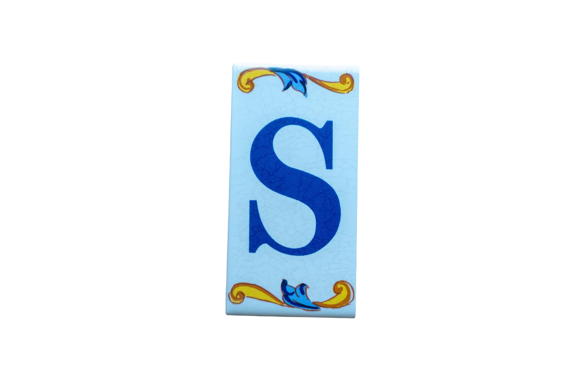 Lisa Croquets Letters – Ceramic House Letter Tiles rectangular tile featuring a blue letter S flanked by decorative yellow and blue scrollwork.