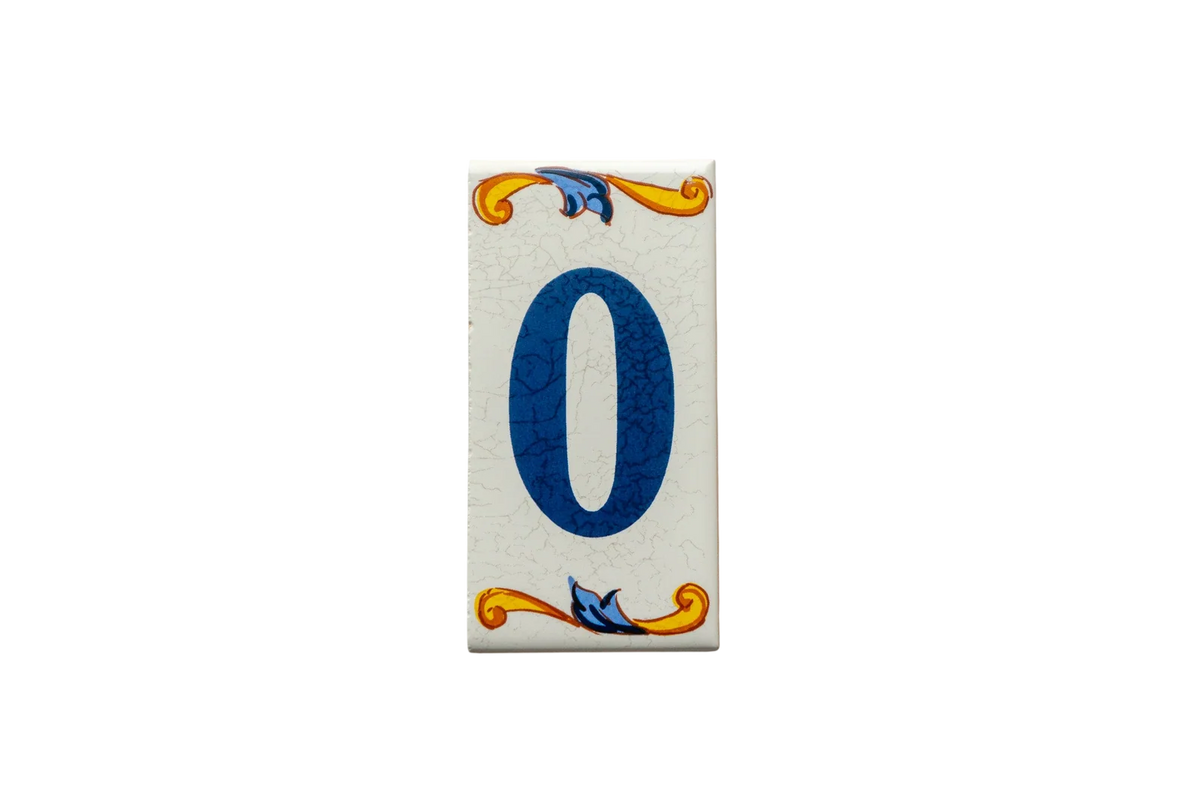 Handcrafted in Spain, this rectangular Lisa Croquets Numbers – Ceramic House Number Tile features the number zero in blue, accented by decorative yellow and blue scrollwork at the top and bottom.