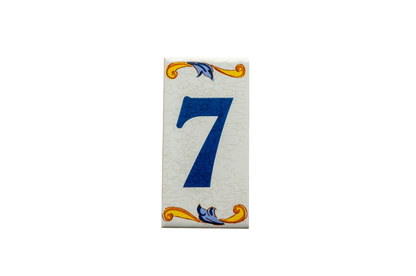 Lisa Croquets Numbers – Ceramic House Number Tiles from LVR Ceramics feature a rectangular shape with a blue number 7 and decorative yellow and blue scrolls at the top and bottom, handcrafted in Spain.