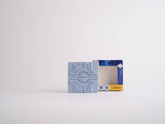 A Sintra Aromatic Tile Magnet by Manulena, inspired by Portugal’s enchanted hills, is shown in front of its opened blue and yellow Lisboa packaging on a plain white background.