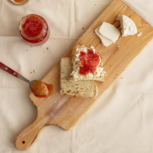 tomato jam served on a wooden board with fresh cheese