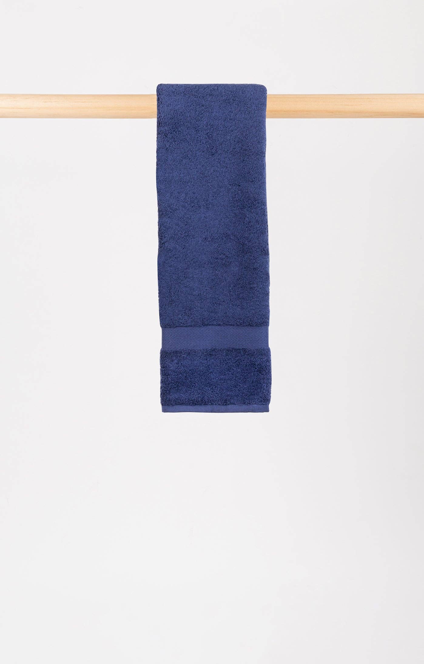 cobalt blue body towel hanging on a wooden rail